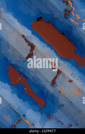 Strukturierter, verrosteter Grund aus geripptem Grund - abblätternder Lack auf der alten Metalloberfläche, blau lackiert mit Rissen und Rost, ein Element eines alten Gebäudes Stockfoto