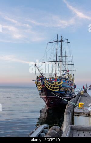 SOPOT, POLEN - 20. Jun 2021: Eine vertikale Aufnahme einer Piratenschiffattraktion, die während des Sonnenuntergangs in Sopot, Polen, an die Docks gebunden ist Stockfoto