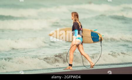 Playa Hermosa, Guanacaste, Costa Rica - 07.26.2020: Eine junge Kaukasierin geht mit einem Surfbrett zum Meer