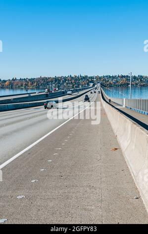 Mann, der in einem Fußgängerweg auf der rechten Seite des Fotos auf der Brücke über den Lake Washington, Eastgate Area, in der Nähe von Bellevue, Washington, unterwegs ist. Stockfoto