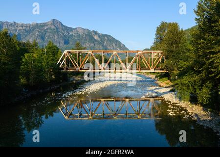 Index, WA, USA - 25. August 2021; EIN Warren durch eine Fachwerkbrücke über die North Fork des Skykomish River in Index WA, gebaut vom Great Northern Stockfoto