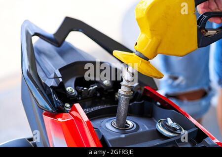 Tanken eines Motorrads. Nahaufnahme einer Kraftstoffdüse, die in einen Gastank eingesetzt ist. Stockfoto