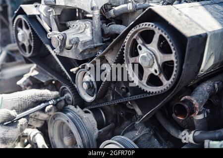 Der Automotor wird von der Seite des Riemens und der Steuerrollen in geringer Schärfentiefe demontiert Stockfoto