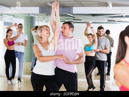 Männer und Frauen unterschiedlichen Alters tanzen Salsa im Tanzsaal Stockfoto