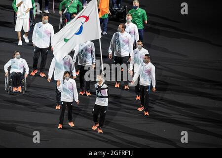 Tokio, Japan. August 2021. Mitglieder des Flüchtlingsteams gehen mit ihrer Nationalflagge im Stadion als Teil der Parade der Athleten Tokyo 20202 Paralympische Spiele Eröffnungszeremonie auf dem Olympiastadion. Die Spiele wurden wegen der weltweiten COVID-19-Pandemie verschoben und ohne Zuschauer abgehalten. Nur Schulkinder in kleinen Gruppen durften während der Spieldauer einige der Veranstaltungen beobachten. (Foto von Lev Radin/Pacific Press) Quelle: Pacific Press Media Production Corp./Alamy Live News Stockfoto