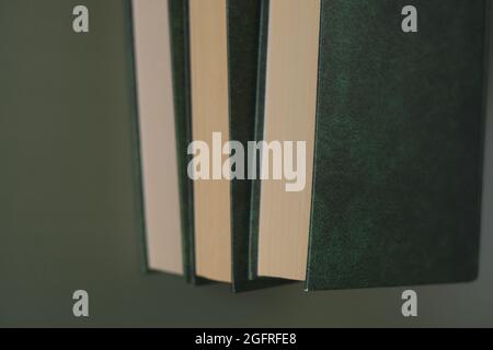 Lesen von Büchern. Wissen und Bildung. Bücher stapeln mit grünen Einbänden auf dunkelgrünem Hintergrund. Geschäftsliteratur und Schulungen. Stockfoto