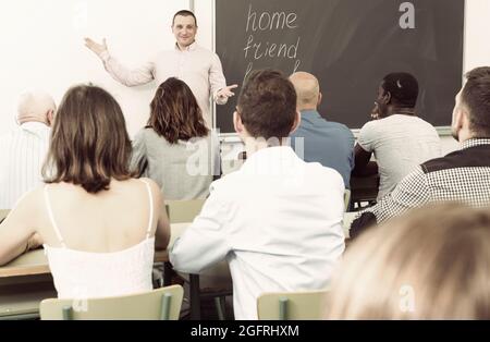 Selbstbewusster Dozent im Gespräch mit Studenten unterschiedlichen Alters Stockfoto