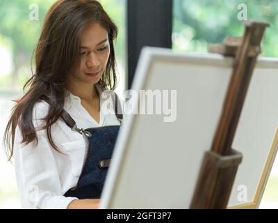 Nahaufnahme, selbstbewusste weibliche Malerin Malerei auf Leinwand, schaffen Meisterwerk, Fokus und inspirieren Stockfoto
