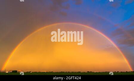 Ein wunderschöner Regenbogen bei Sonnenuntergang nach einem Sommergewitter Stockfoto