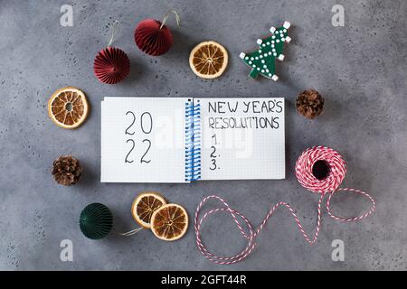 Das Wort Neujahrsauflösung, geschrieben in einem weißen Notizbuch auf einem grauen Neujahrshintergrund. Speicherplatz kopieren. Stockfoto