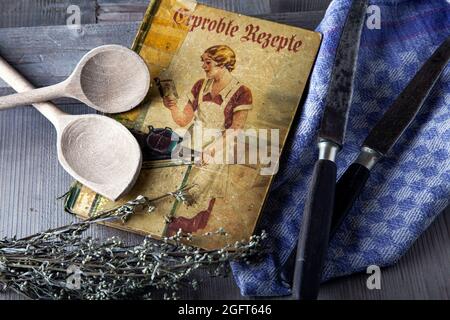Antikes Kochbuch mit Holzlöffel und Messer Stockfoto