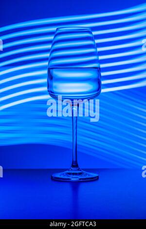Kristallglas mit reinem Wasser auf dem hellen Hintergrund gemalt. Studioaufnahme, Blautöne, Oberflächenreflexionen. Stillleben Fotos, Getränke Stockfoto