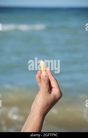 Glatter Kieselstein Nahaufnahme in der Hand auf dem Hintergrund des Meeres, Seekiesel Stockfoto