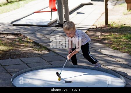 Umea, Norrland Schweden - 10. August 2021: Kleiner netter Kerl spielt Minigolf Stockfoto