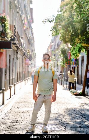 Junger Latino-Mann, der durch die Straßen der Stadt spazierengeht. Lateinischer Mann in Jeans und grünem Poloshirt. . Hochwertige Fotos Stockfoto