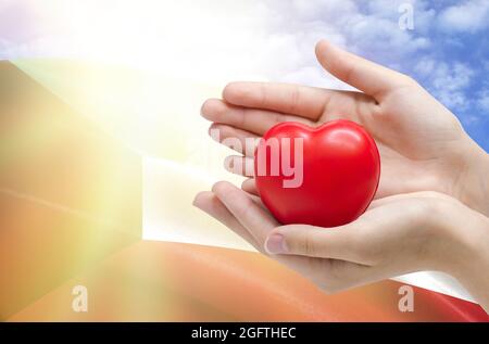 Die Hände des Kindes halten ein Herz auf dem Hintergrund der Flagge von Kuwait, Gesundheitskonzept. Stockfoto