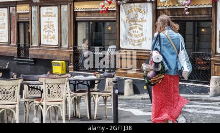 Paris, Frankreich - Juli 2021: Junge Frau, die Lebensmittel aus Plastik und Gemüse in einer wiederverwendbaren Tasche auf der Straße in Paris trägt.Monmartre Street. Stockfoto