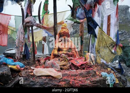 Ein Hindu-Idol, umgeben von buddhistischen Gebetsfahnen, die nach den Gebeten am Tag von Janai Purnima mit Farben bedeckt waren Stockfoto