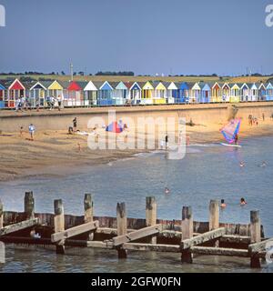 1999 Archiv close up Magier von großen Holz 1990er Wellenbrecher Groyne Struktur in der Nordsee Schutz der Küste & Küstenlinie in Southwold Badeort mit Menschen schwimmen und Windsurfen farbenfrohe Strandhütten dahinter auf der Betonwand Promenade In den 90er Jahren Blue Sky Summer Day Archivansicht der Suffolk Küste in East Anglia England Großbritannien Stockfoto