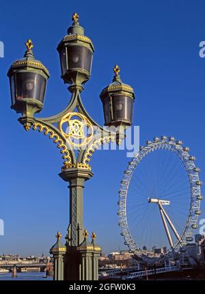 Antikes und modernes Archiv 1999 Ansicht des London Eye Riesenrads in Position bereit für seine feierliche Eröffnung Das neue Jahr 2000 feiert ein berühmtes Wahrzeichen jenseits einer Nahaufnahme des historischen Archivbildes der 1990er Jahre Viktorianisches drei Cluster Straßenlaternen auf gusseisernen Säulen an der Westminster Road Bridge ein Vergleich der auffälligen Flussseite Strukturen in London England Vereinigtes Königreich Stockfoto