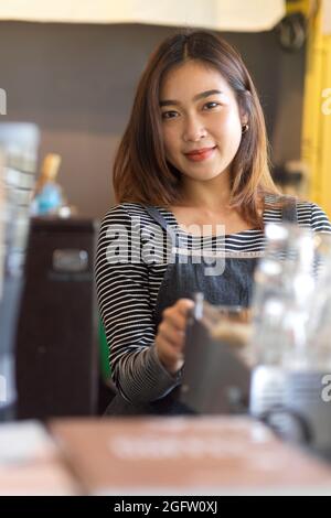 Porträt einer hübschen jungen Barista, die im Café, im Café und in der Geschäftsbesitzerin lächelt Stockfoto