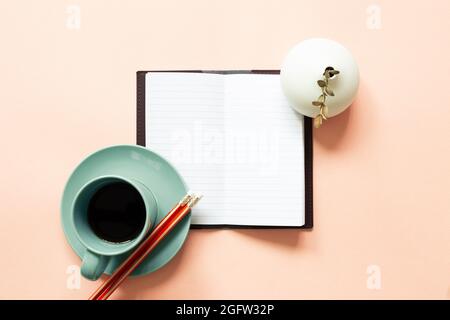 Offenes Notizbuch, Tasse Kaffee, Bleistift, Eukalyptus auf rosa Hintergrund. Arbeitsbereich. Draufsicht, Kopierbereich Stockfoto