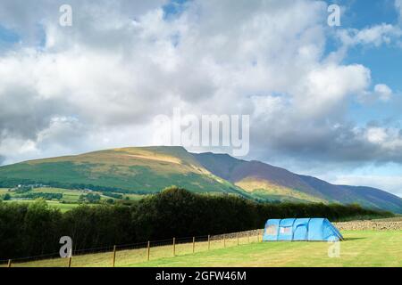 Zeltlager auf einem Farmfeld im Lake District gegenüber der Blencathra (Saddleback) fielen an einem bewölkten, nebligen Sommertag. Stockfoto