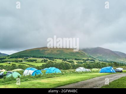 Zeltlager auf einem Farmfeld im Lake District gegenüber der Blencathra (Saddleback) fielen an einem bewölkten, nebligen Sommertag. Stockfoto