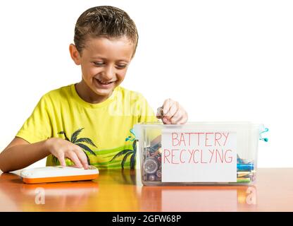 Ein Kind, das eine leere Batterie aus einem Spielzeug herausgenommen und in einen Recyclingbehälter gestellt hat. Konzept der Erziehung von Kindern in Umweltwerten. Weißer Hintergrund Stockfoto