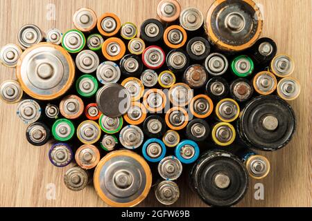 Flache Batterien ordentlich auf einem Holztisch platziert. Konzept des Recyclings und der Pflege der Umwelt. Stockfoto