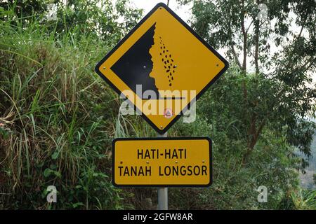 Gelbes Schild mit natürlichem Hintergrund. Hati-hati tanah longsor bedeutet Vorsicht vor Erdrutschen Stockfoto