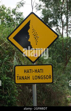 Gelbes Schild mit natürlichem Hintergrund. Hati-hati tanah longsor bedeutet Vorsicht vor Erdrutschen Stockfoto