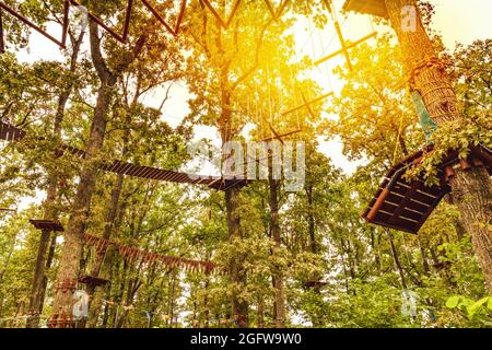 Hängebrücke, Gehweg Treppe zum abenteuerlichen, Baumkronen Kreuz auf die andere Seite.Seilpark unter den Bäumen. Stockfoto