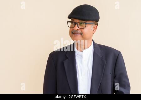 Porträt eines gutaussehenden indischen Geschäftsmannes mit Schnurrbart, der einen Hut an der schlichten Wand trägt Stockfoto
