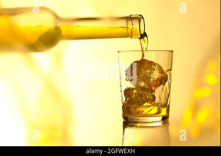 Den Whiskey in ein Glas mit Eiswürfeln gießen Stockfoto