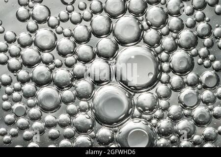 Ölblasen im Wasser bilden ein Interessantes stahlgraues Makromuster Stockfoto