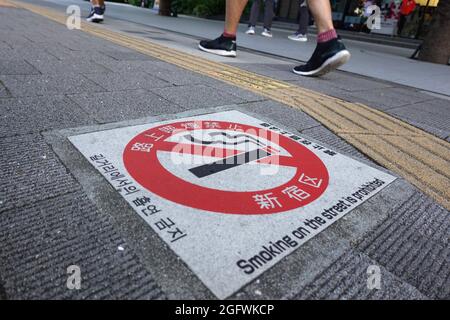 Tokio, Japan. August 2021. Auf einem Bürgersteig laufen die Leute an einem Rauchverbot vorbei. Kredit: Marcus Brandt/dpa/Alamy Live Nachrichten Stockfoto