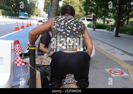 Tokio, Japan. August 2021. Ein Mann verkauft oder tauscht Pins auf einem Bürgersteig. Kredit: Marcus Brandt/dpa/Alamy Live Nachrichten Stockfoto