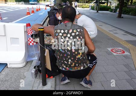 Tokio, Japan. August 2021. Ein Mann verkauft oder tauscht Pins auf einem Bürgersteig. Kredit: Marcus Brandt/dpa/Alamy Live Nachrichten Stockfoto