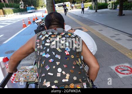 Tokio, Japan. August 2021. Ein Mann verkauft oder tauscht Pins auf einem Bürgersteig. Kredit: Marcus Brandt/dpa/Alamy Live Nachrichten Stockfoto