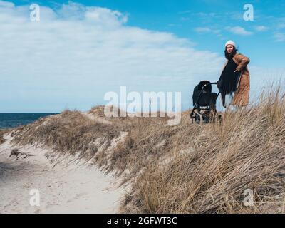 Frau mit Kinderwagen, die auf Sanddünen steht Stockfoto