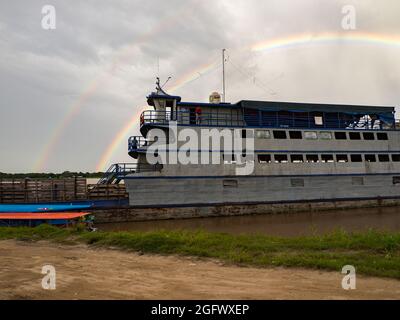 Amazonas, Peru - 07. Dezember 2019: Blick auf das langsame Boot 'Maria Fernanda' und Regenbogen im kleinen Hafen am Amazonas. Amazonien. Südamerika Stockfoto