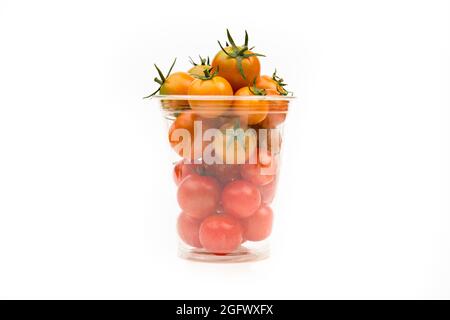 Kirschtomaten in transparentem Kunststoffbehälter auf weißem Hintergrund, Nahaufnahme. Stockfoto