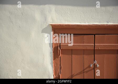 Altes traditionelles Hausfenster mit hölzernen Fensterläden an einer weiß getünchten Wand in Thiseio, Athen, Griechenland. Stockfoto