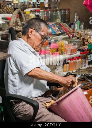 Iquitos, Peru - Dez 2019: Porträt eines alten Mannes, der auf dem Stuhl sitzt und verschiedene Dinge verkauft, die der Belen Basar (Belén Markt), Iquitos - Tor zu Stockfoto