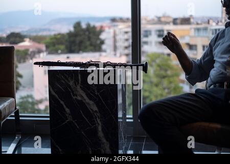 IZMIR, ALSANCAK, Türkei. August 2021. Geschäftsmann spielt seine Klarinette in seinem Büro nach der Arbeit für die Entspannung in einem Büro in Izmir-Türkei. Izmir ist eine Metropole im westlichen Teil Anatoliens. Sie ist nach Istanbul und Ankara die drittbevölkerungsreichste Stadt der Türkei und nach Athen die zweitgrößte städtische Agglomeration an der Ägäis. (Bild: © Uygar Ozel/ZUMA Press Wire) Stockfoto