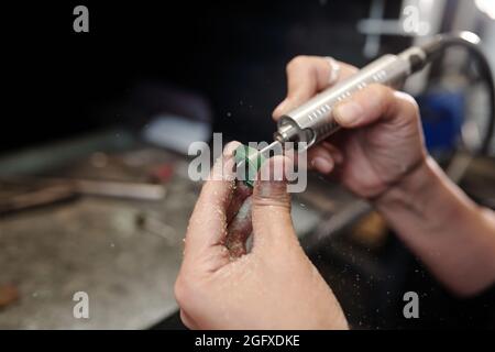 Nahaufnahme eines nicht erkennbaren weiblichen Juwelierrings mit Polierwerkzeug in der Werkstatt Stockfoto