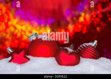 Rote weihnachtsornamente auf Schnee vor einem zauberhaft funkelnden Hintergrund, Text- oder Textraum. Stockfoto