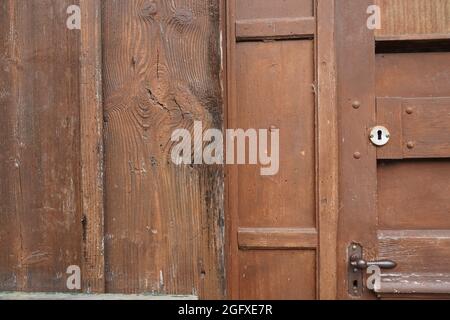 Nahaufnahme einer braunen geschlossenen Tür mit Türgriff und Schlüsselloch in einem alten Holzhaus. Stockfoto