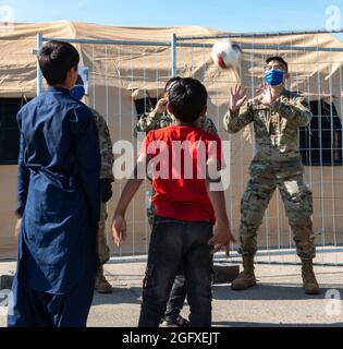 US Air Force Airmen, die dem Luftwaffenstützpunkt Ramstein zugewiesen wurden, werfen auf dem Luftwaffenstützpunkt Ramstein, Deutschland, am 25. August 2021 einen Ball an gefährdete afghanische Kinder. Der Flugplatz Ramstein hat Kindern Tausende von Spielzeug und Kleidung zur Verfügung gestellt, die sowohl den Lebensstandard als auch die Moral erhöhen. Ramstein, ein vorübergehender Ort für Evakuierte aus Afghanistan, bietet vorübergehend Unterkunft, Nahrung, medizinische Versorgung und Behandlung an, während sie auf den Transport zu anderen Umsiedlungsorten warten. Die Ramstein Air Base wurde zum primären Evakuierungszentrum des US European Command, das einen der größten, komplexesten humanitären ai unterstützt Stockfoto